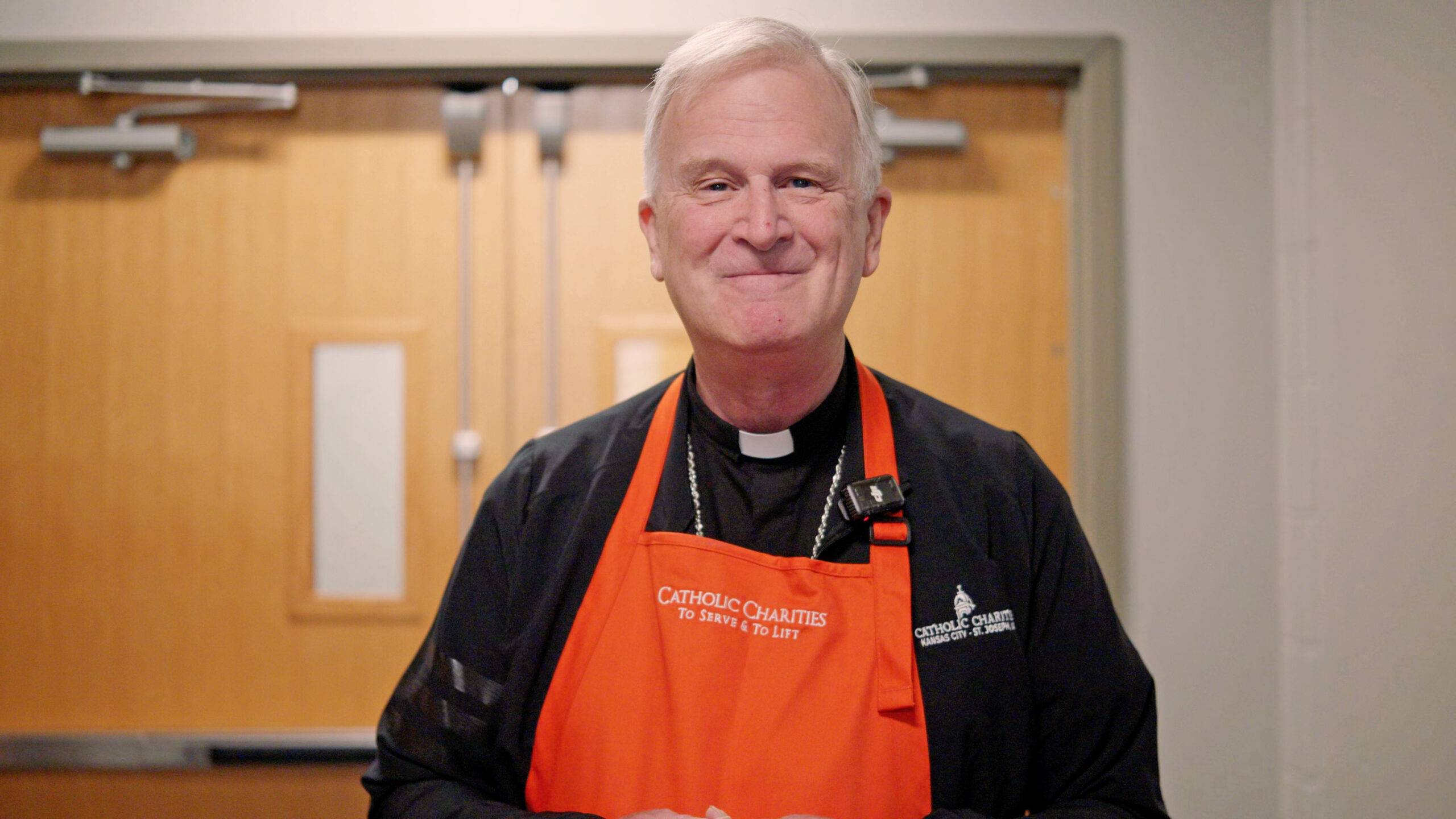 Bishop wearing Catholic Charities apron