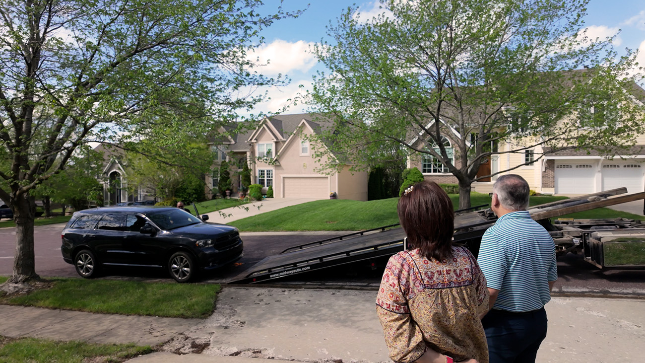 Couple watches car being loaded onto tow truck