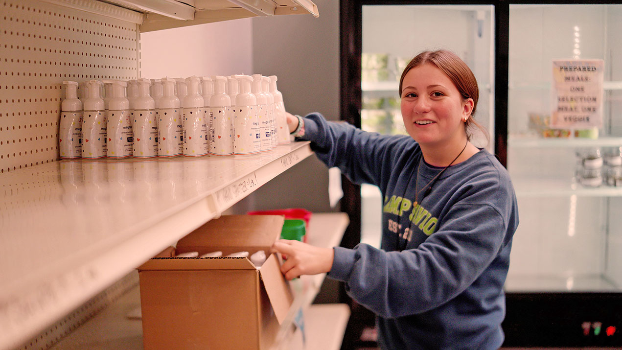Young woman stocking shelves with soap bottles