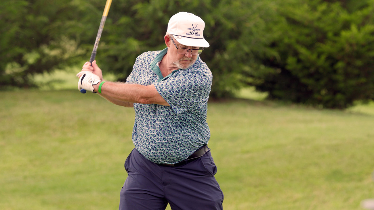 Golfer swinging club on green grass