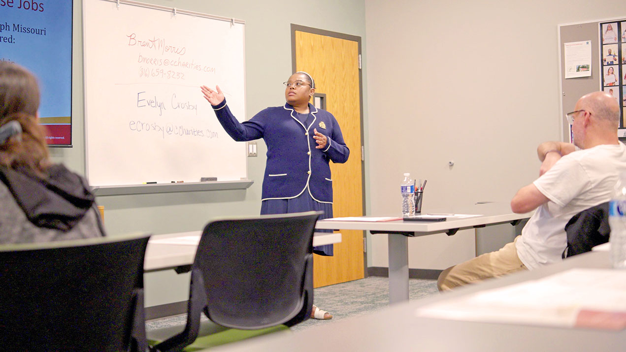 Woman presents at a whiteboard to an audience.