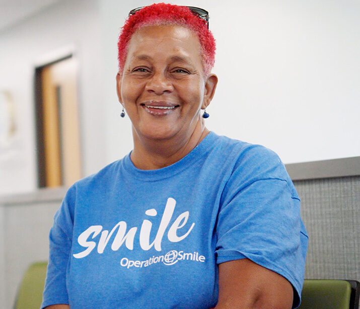 Woman with bright red hair wearing a blue Operation Smile t-shirt