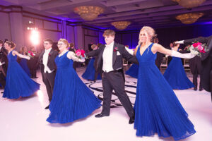 Young people in blue gowns at a formal event.