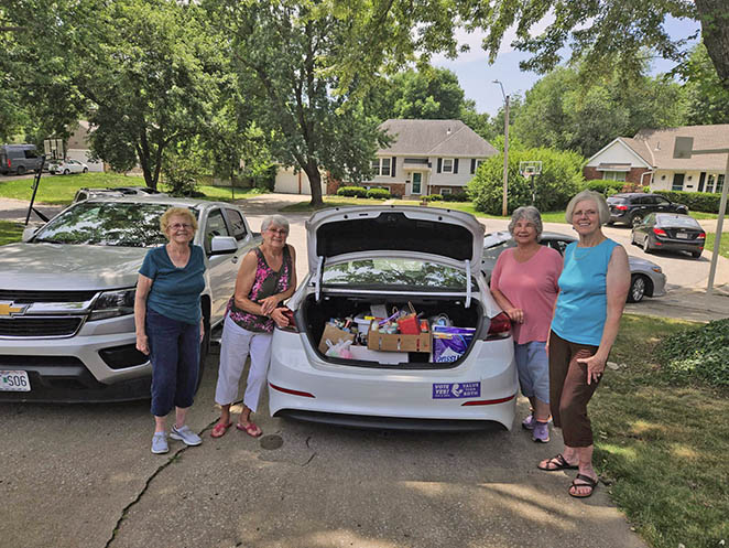 Women load care kits into car trunk