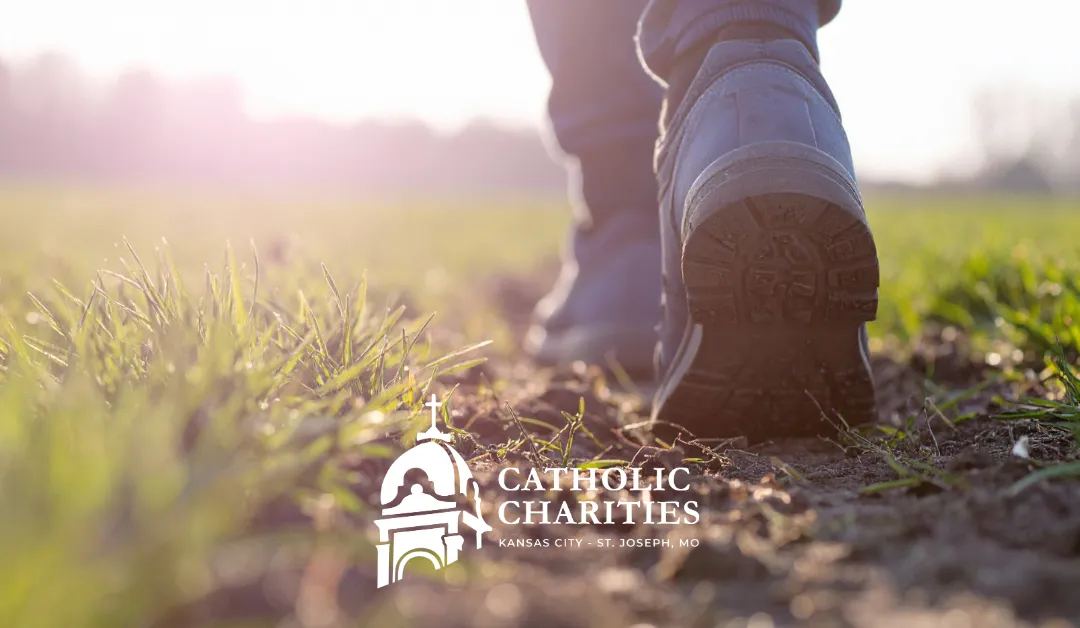 Person walking in field with Catholic Charities logo
