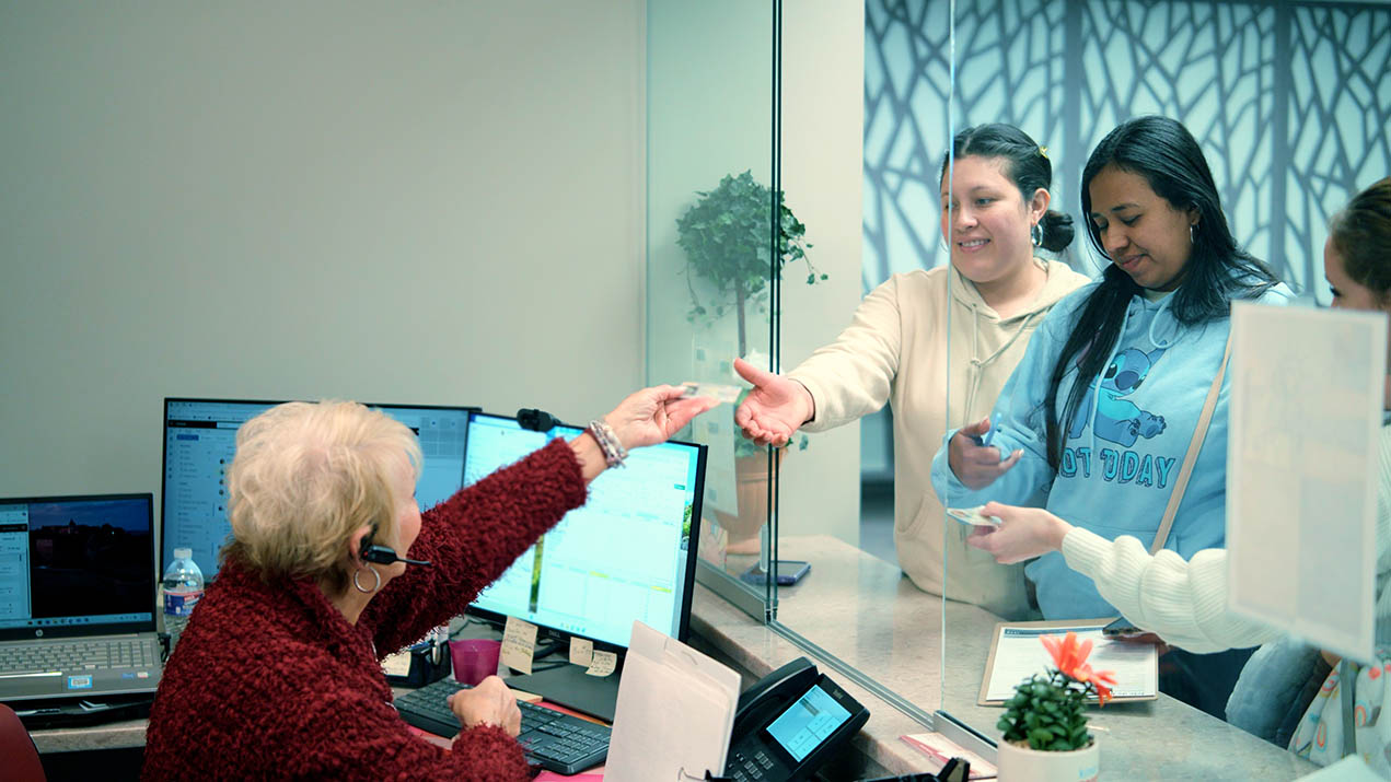 Woman hands ID to receptionist