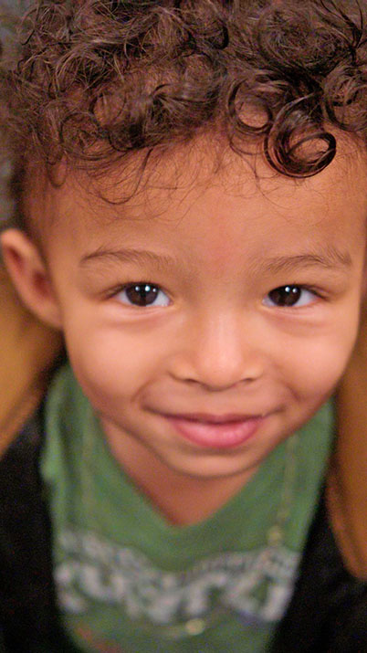 Close-up of a smiling young boy with curly hair