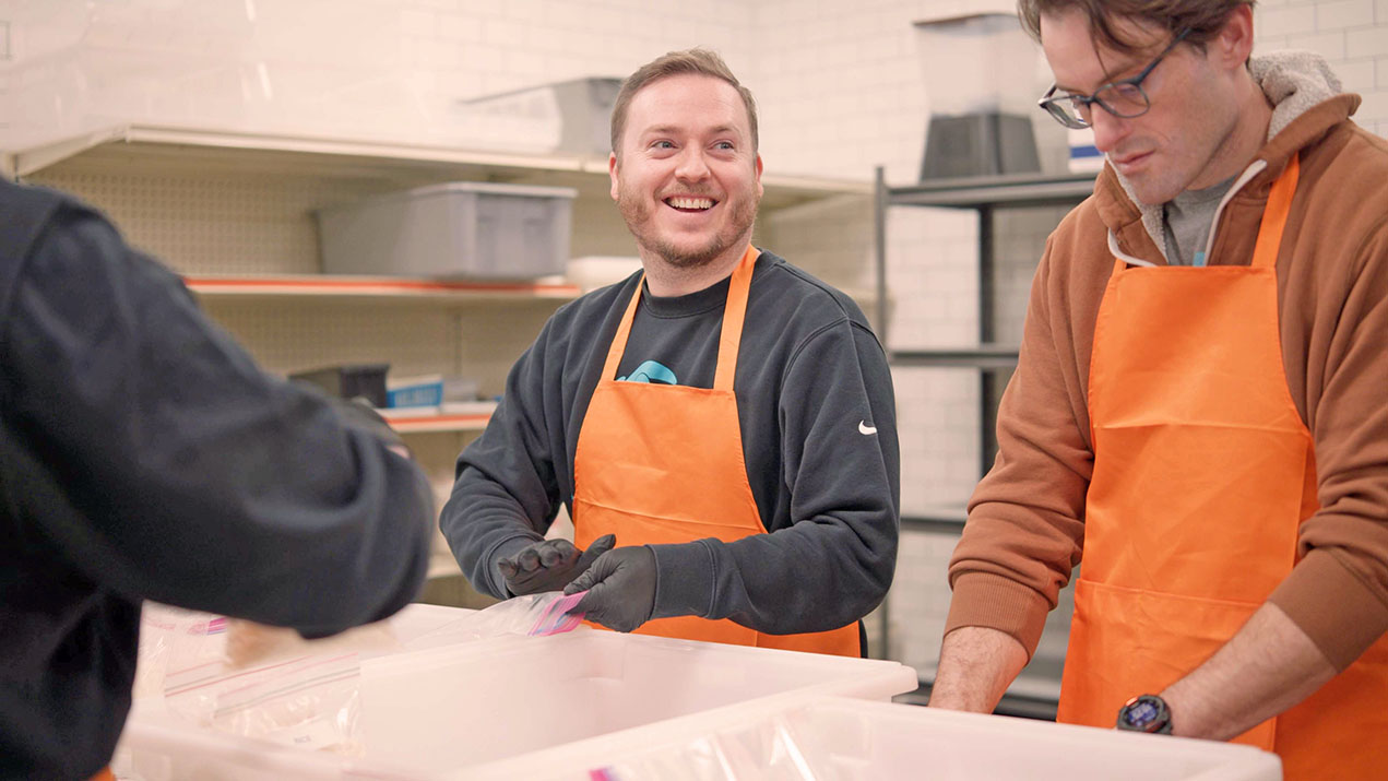 Volunteers packing food in orange aprons