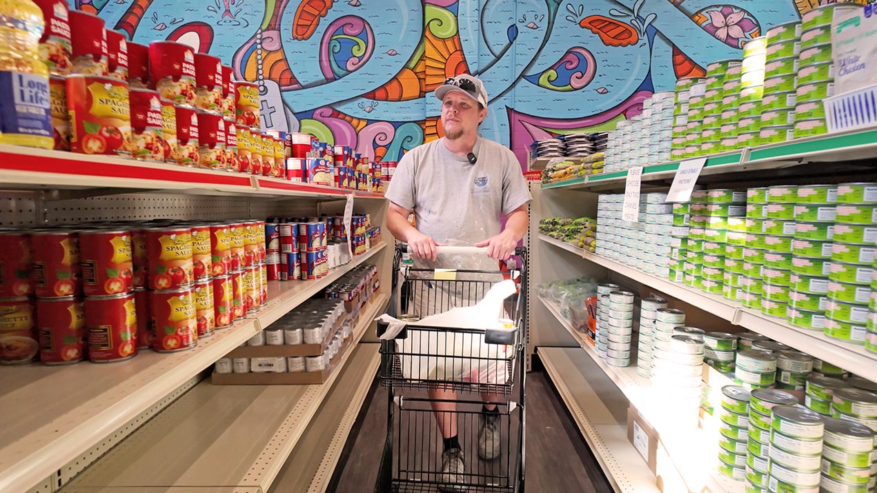 Man in food pantry with shopping cart