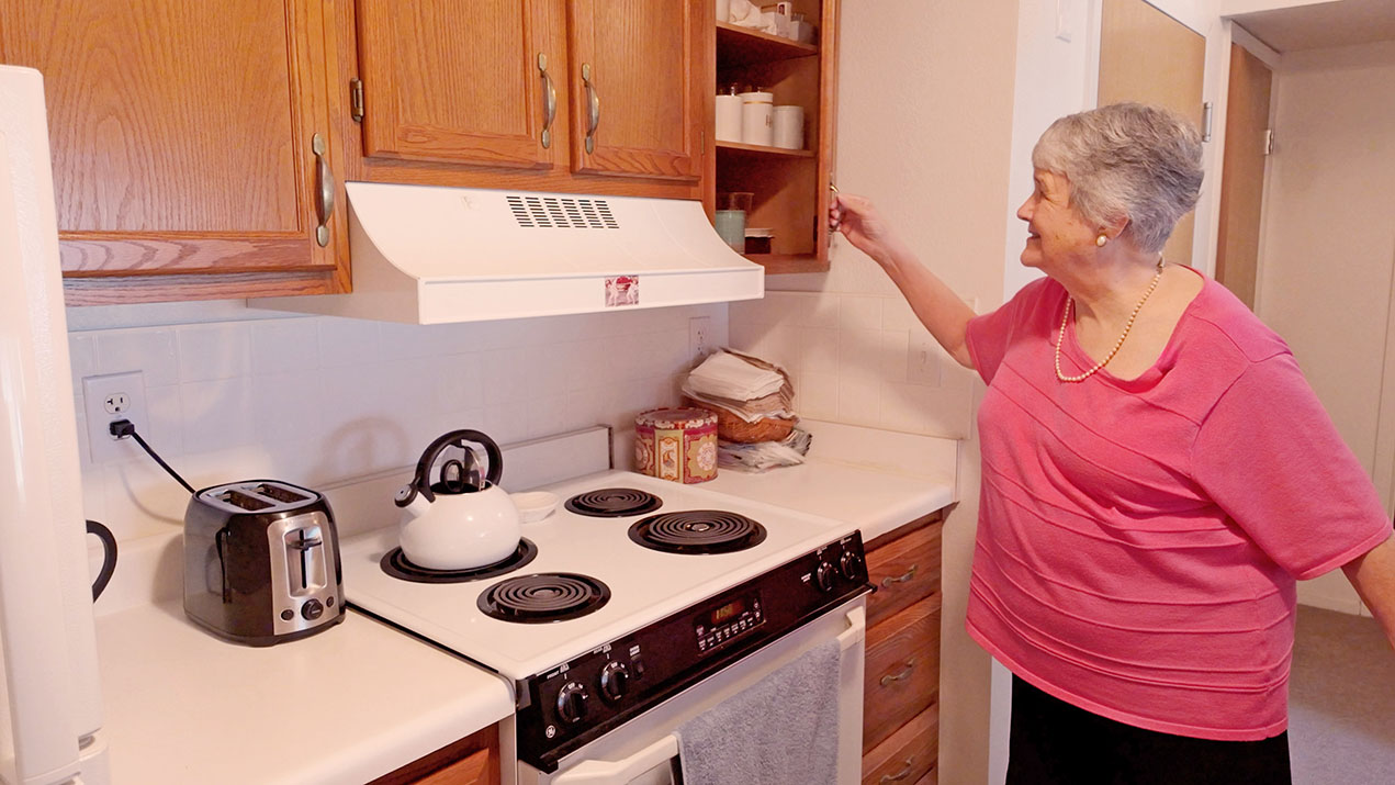 A woman opening her kitchen cabinet