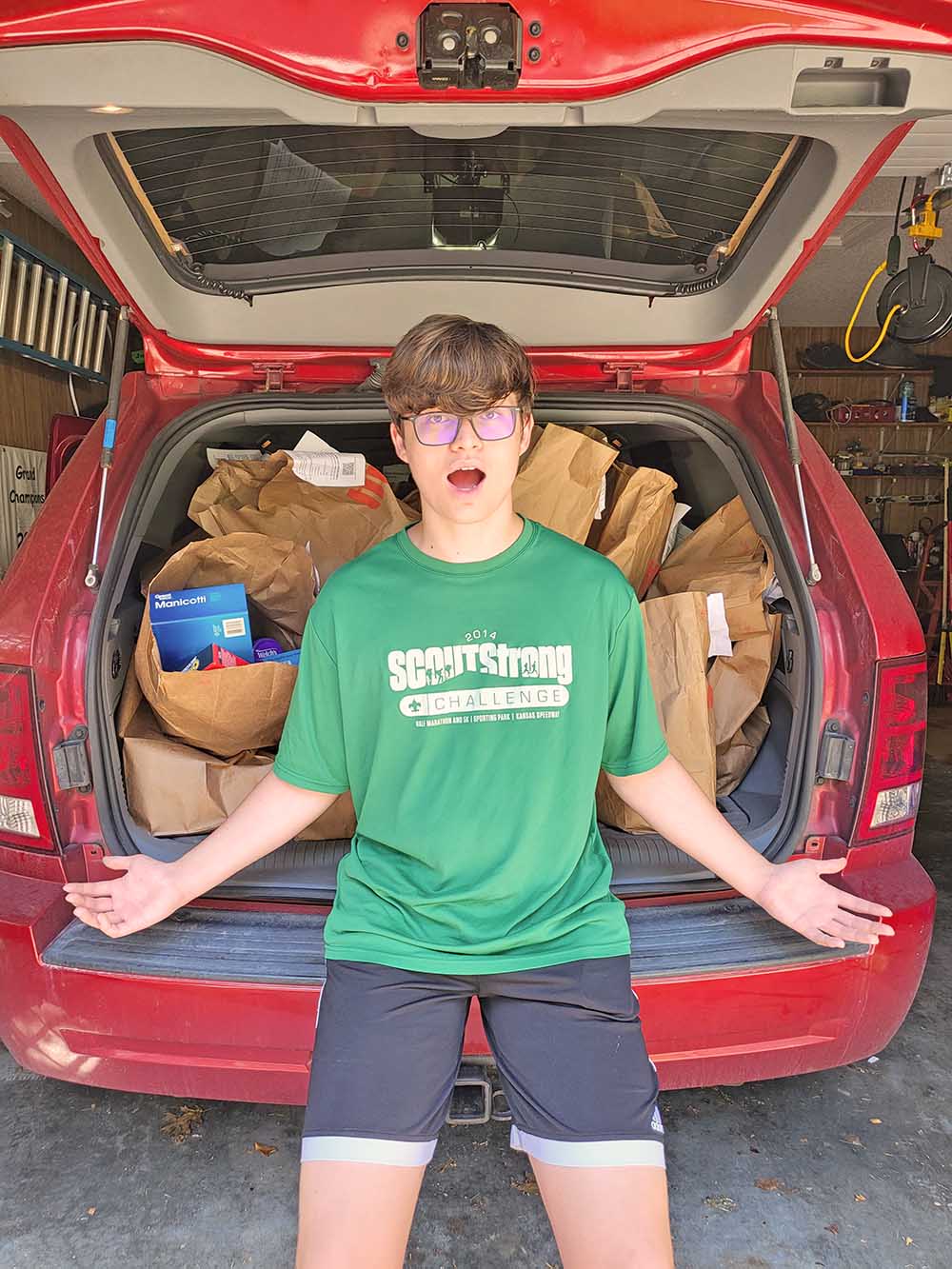 Boy with arms out in front of car trunk