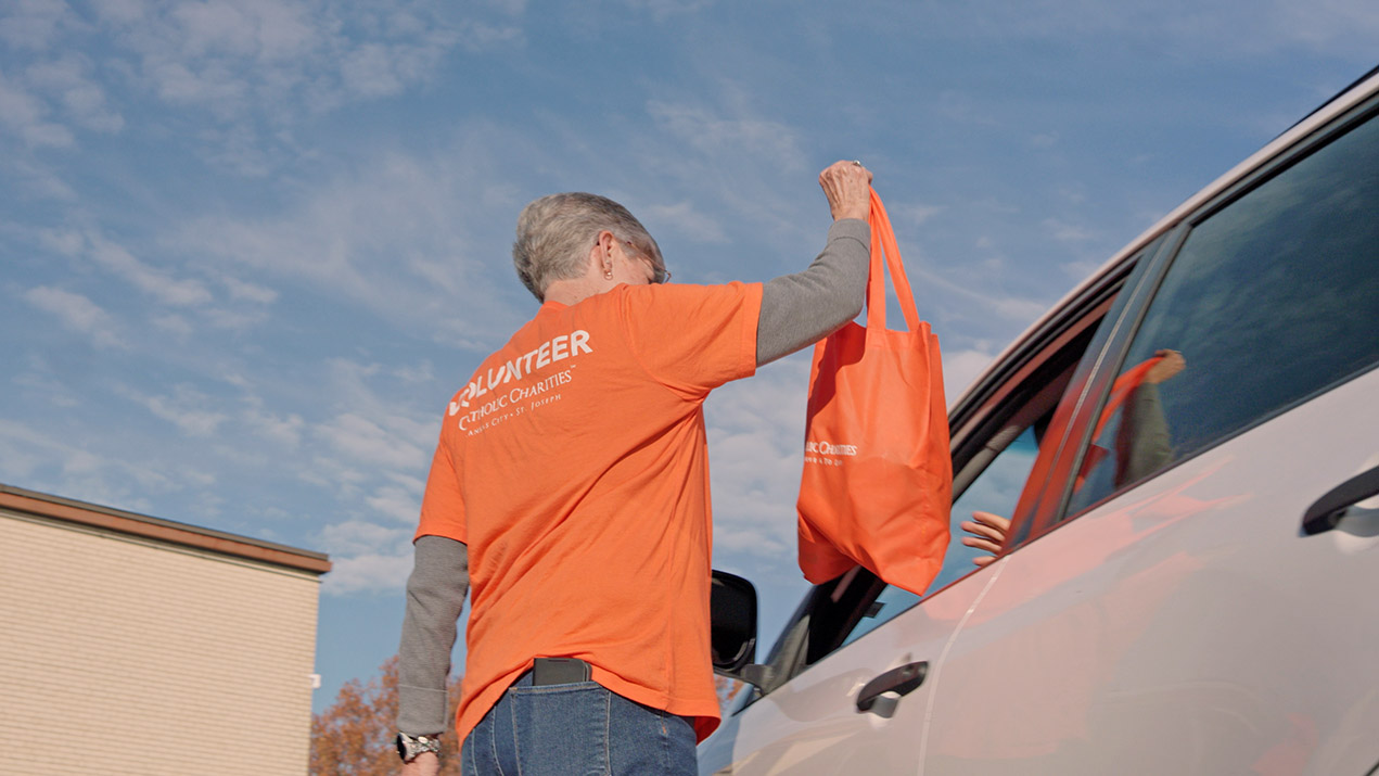 Volunteer hands bag to person in car