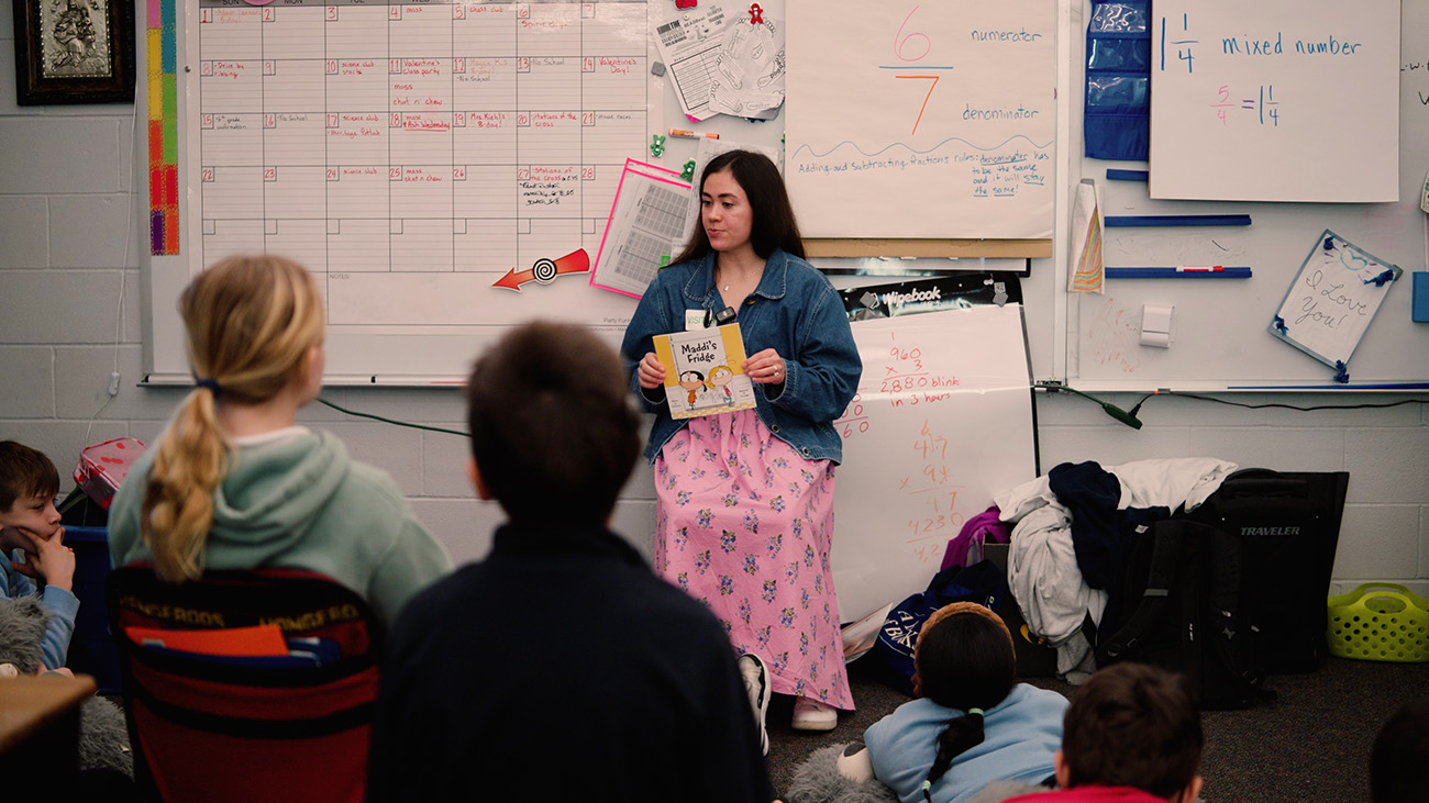 Woman reads to diverse elementary students.