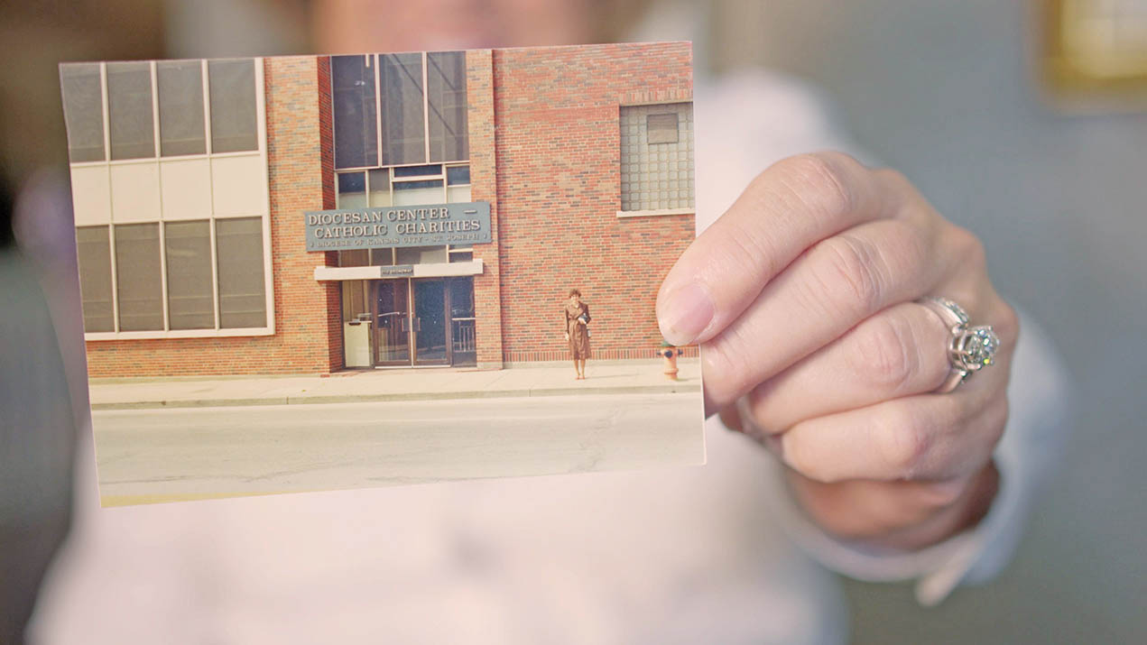 Woman holds old photo of Catholic Charities building