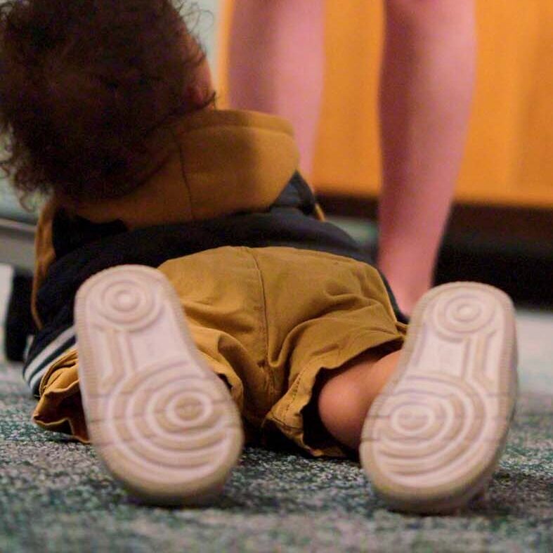 Toddler in yellow shorts laying on the ground
