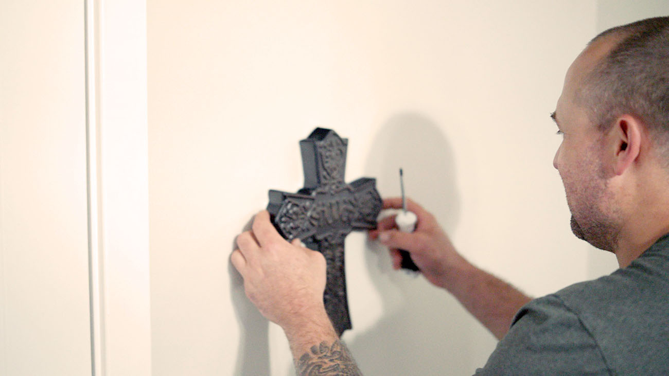 Man hangs ornate cross on wall