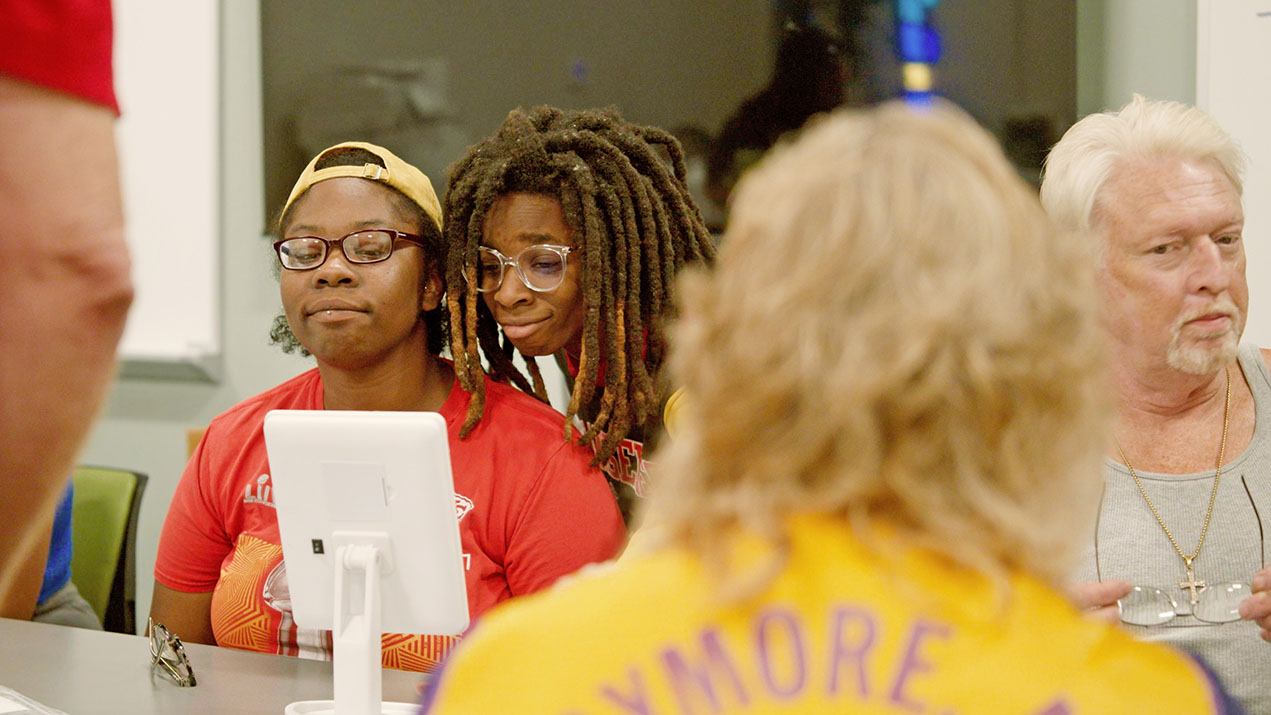 People gathered around a tablet getting eye glasses