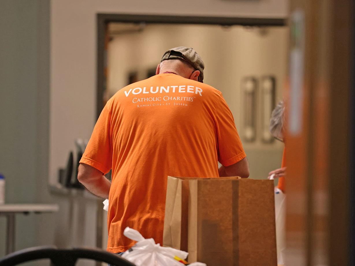 Volunteer in orange shirt at Catholic Charities