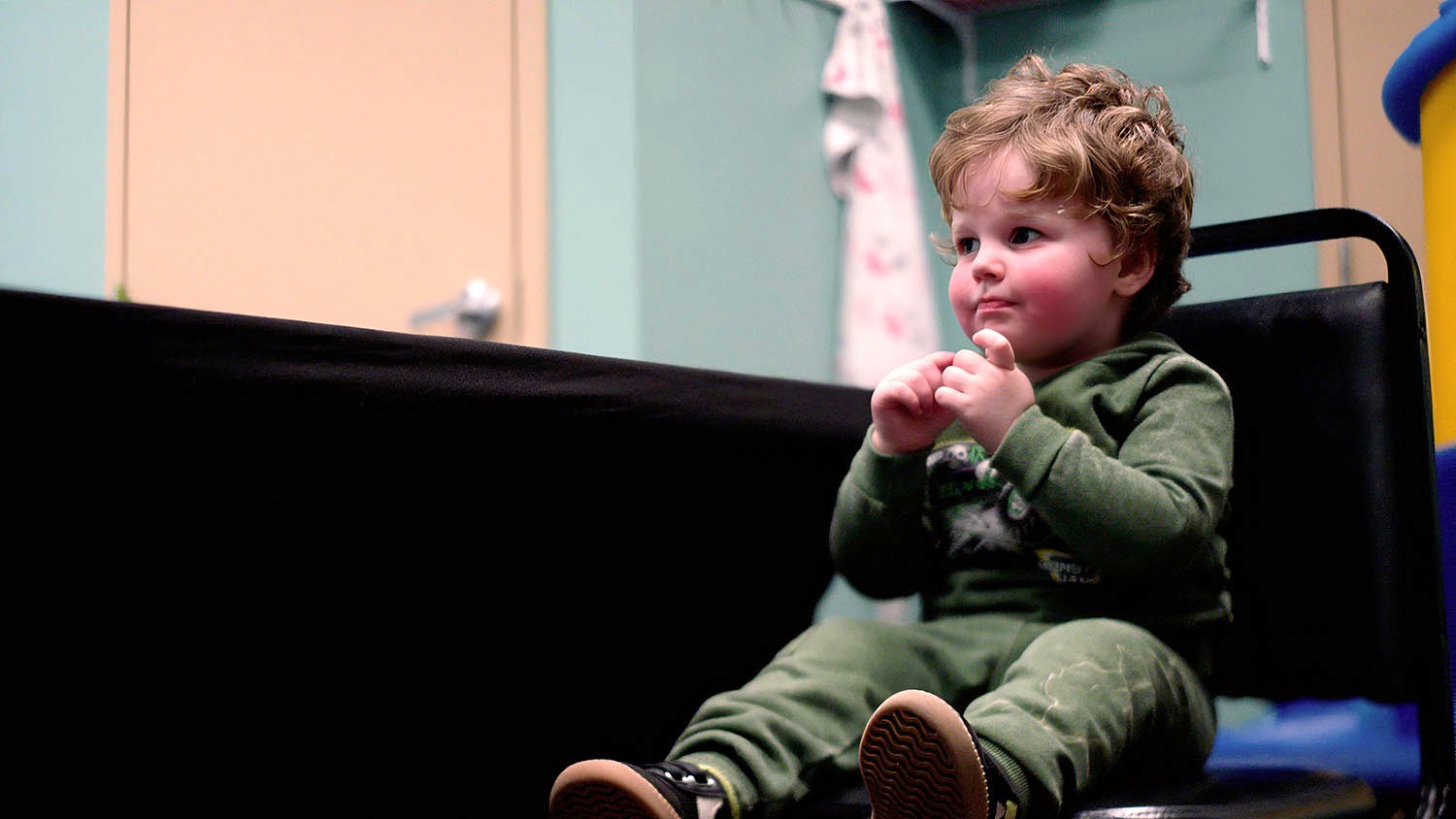 Toddler in green sweatsuit watching something