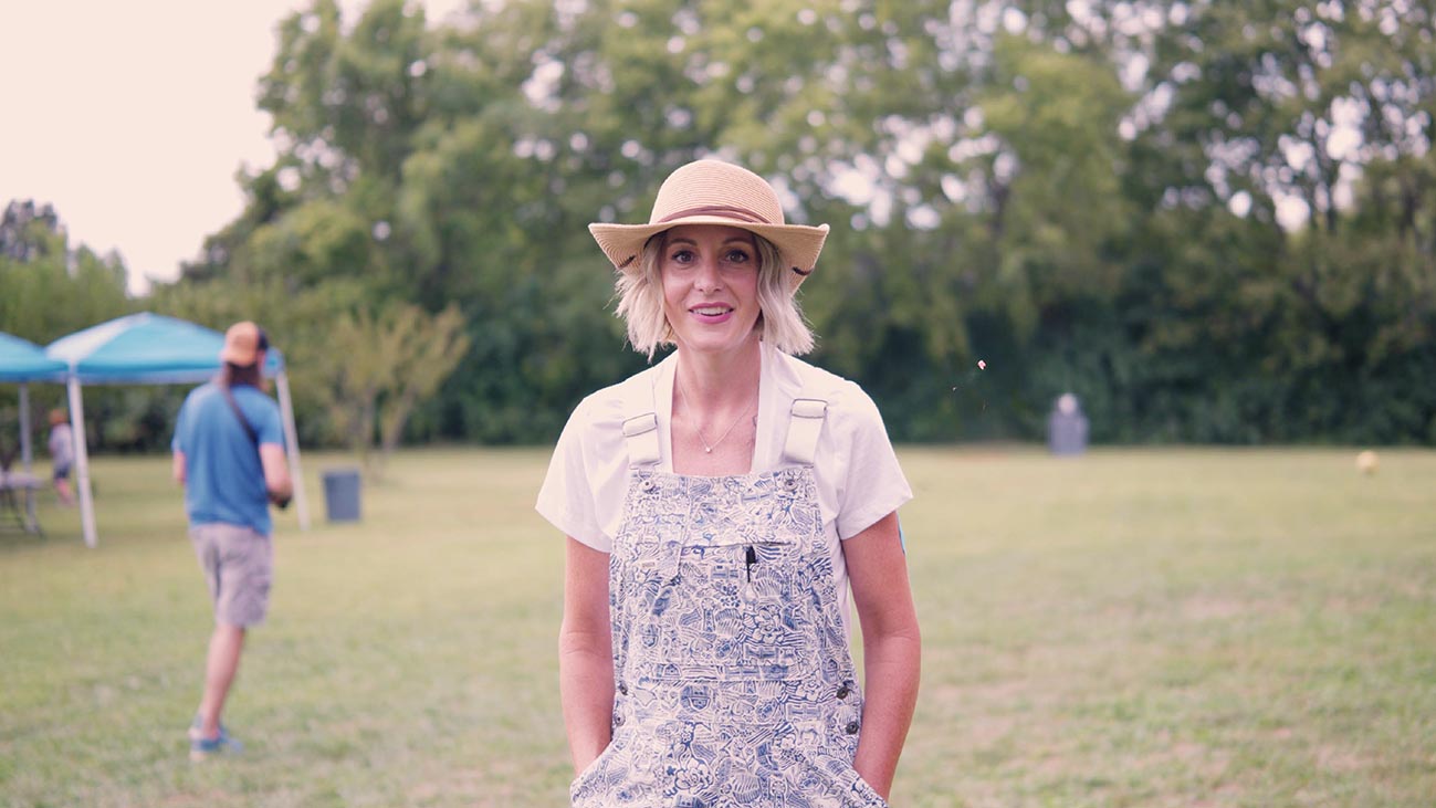 Woman in overalls and straw hat outdoors
